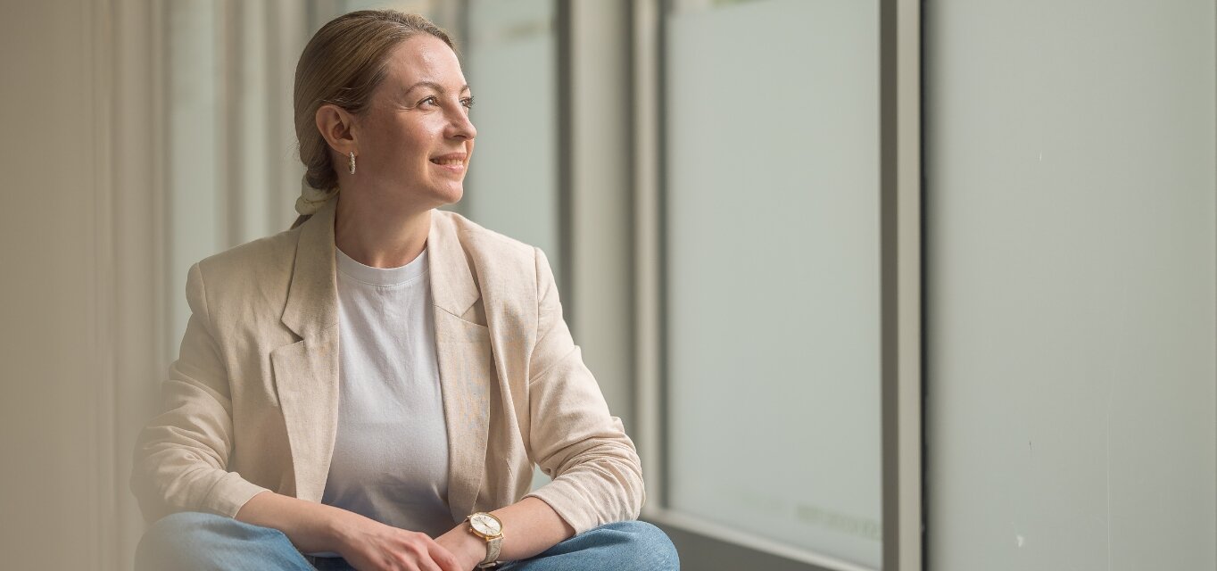 Studierende der KH Freiburg im Schneidersitz, entspannt aus einem Fenster schauend.