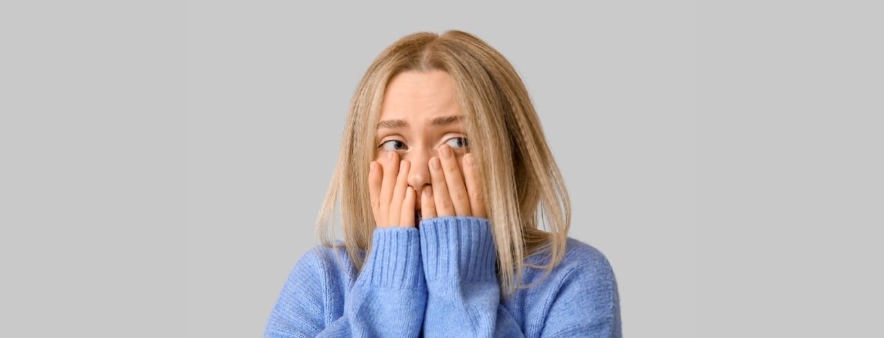 eine Frau hält sich schamerfüllt die Hände vors Gesicht.