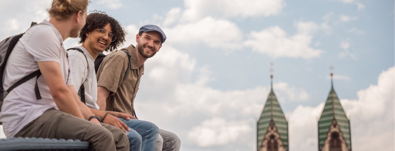 Studierende der KH Freiburg sitzen entspannt auf der Wiwili-Brücke und unterhalten sich