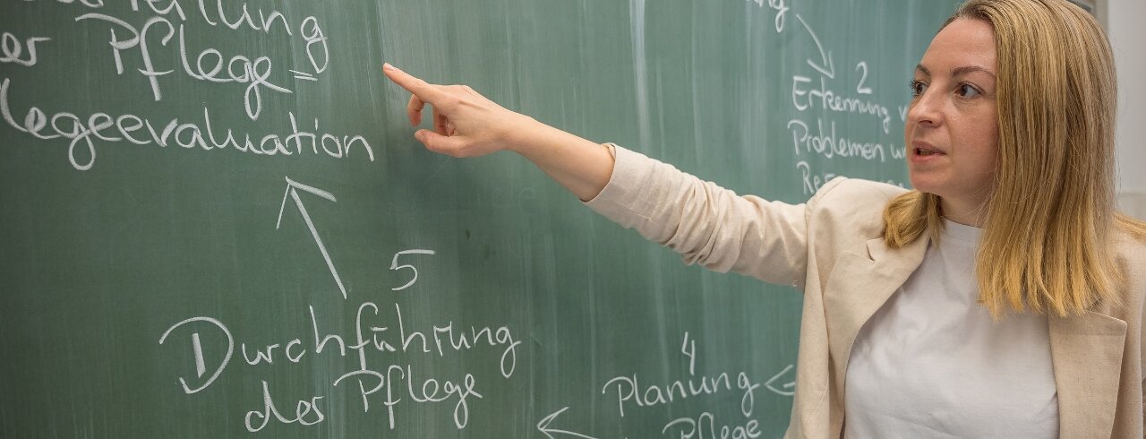Studierende der KH erklärt etwas an der Tafel