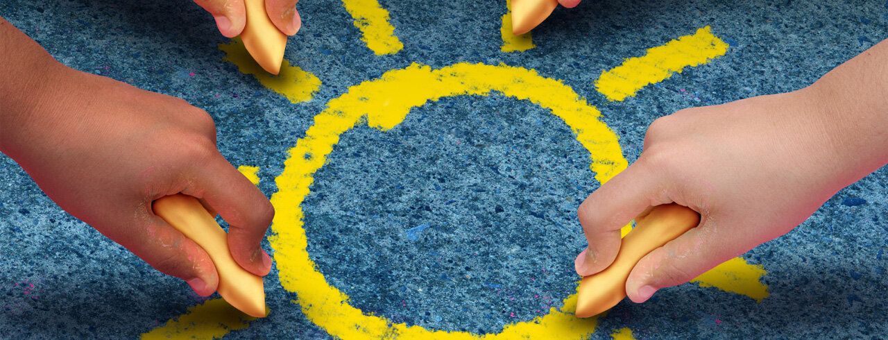 Kinderhände malen eine Sonne auf die Straße