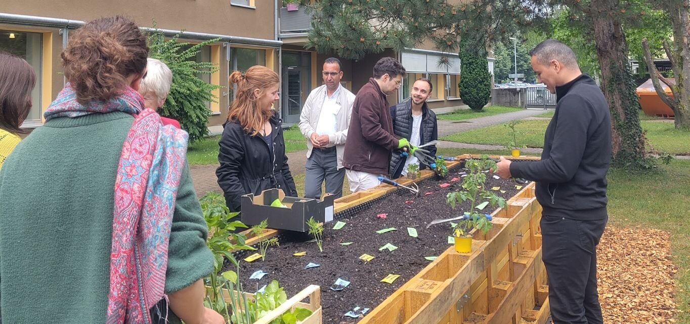 Gemeinsam bepflanzen internationale Studierende, Dozierende und Bewohner*innen des Studentenwohnheims das Hochbeet an Campus II