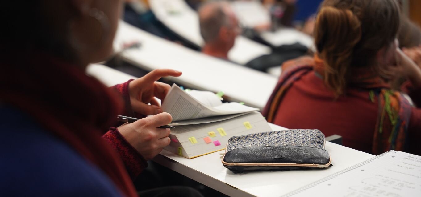 Detailaufnahme: Teilnehmende Person beim Vortrag zur Bürgergeldreform schlägt etwas im Gesetzestext nach